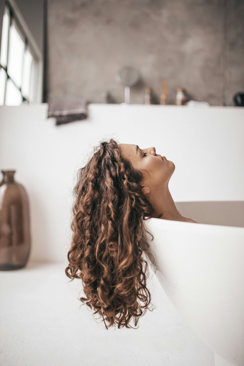 vrouw in bad met krullend haar lekker een moment voor haar zelf