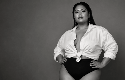 Zelfverzekerde curvy vrouw in zwart-wit, gekleed in een witte blouse en zwarte high-waist lingerie.