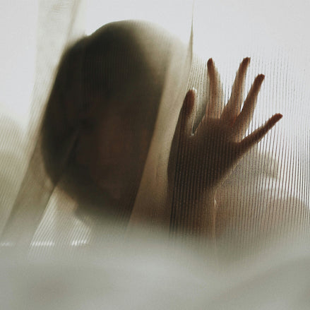 Silhouet achter mat glas in warm licht, intieme sfeer die spanning opbouwen en langzaam voorspel uitstraalt.