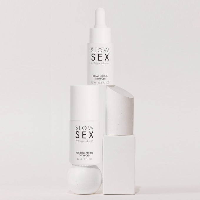 Minimalistische productfoto van Slow Sex CBD oliën op witte objecten voor een luxe en natuurlijke intimiteitsbeleving