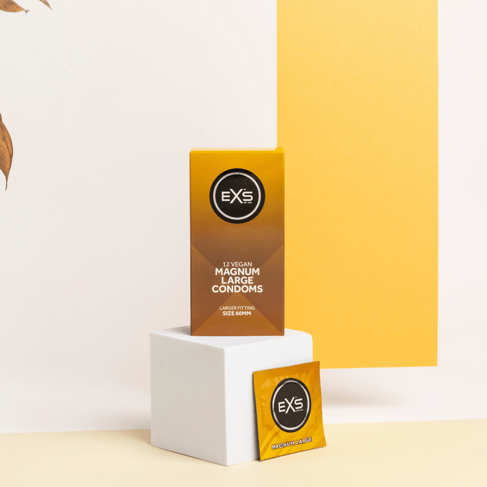 EXS Magnum condooms met doosje en losse sachet in warme studio-opstelling met gele en witte tinten.