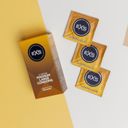 EXS Magnum condooms met doosje en meerdere goudbruine sachets, speels neergelegd op witte en gele vlakken.