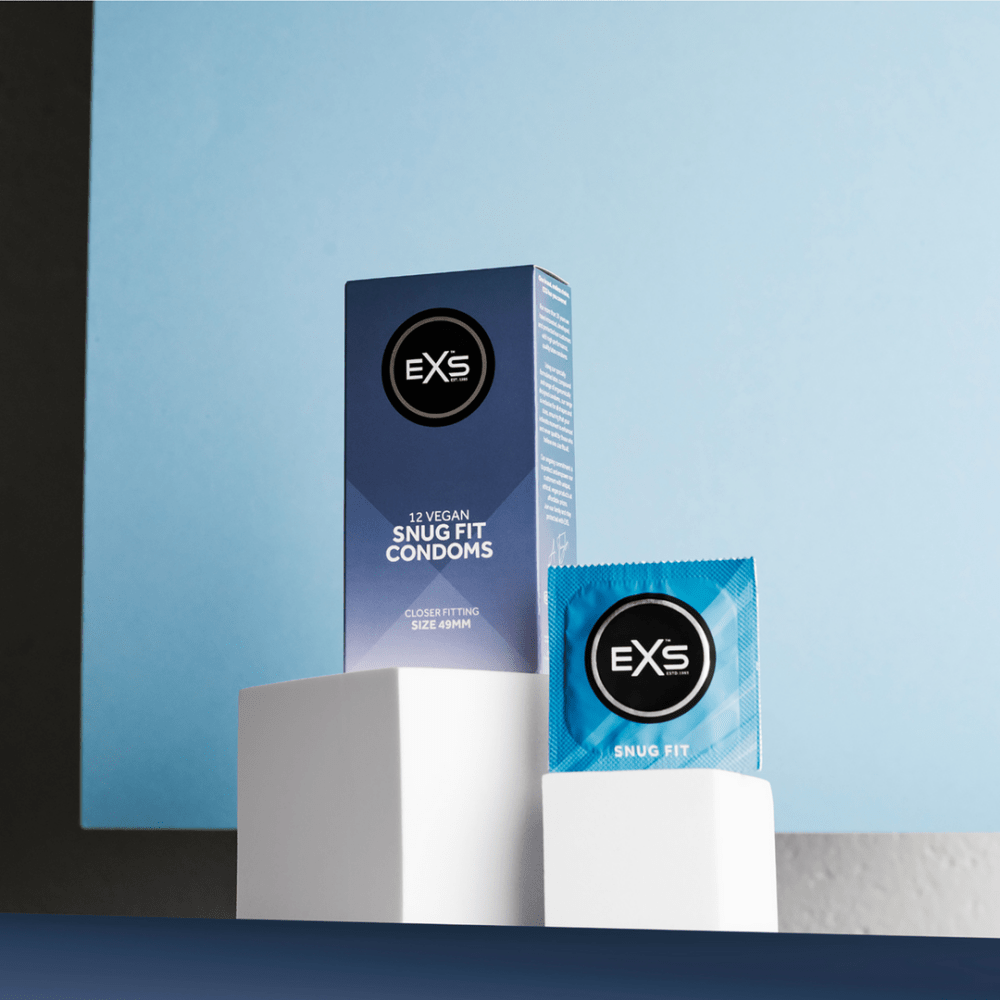 EXS Snug Fit condooms als sfeerbeeld met doosje en losse wrapper op witte sokkels tegen blauwe achtergrond