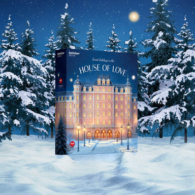 Donkerblauwe Satisfyer Deluxe Adventskalender 2025 doos recht van voren met gouden sterren en sneeuwachtige achtergrond