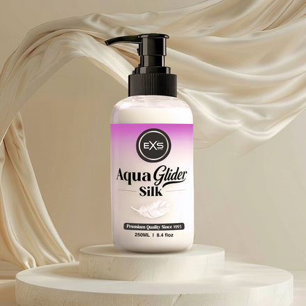 EXS AquaGlider Silk glijmiddelfles op een sokkel met wapperende crèmekleurige zijden stof