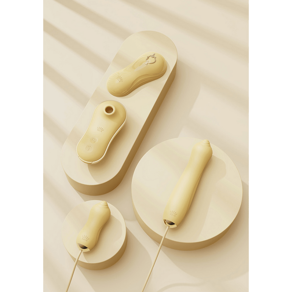 Zalo Unicorn luxe zuigvibrator set in zachte goudtint, artistieke flatlay van drie onderdelen op beige strepen