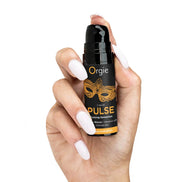 Hand met witte nagels houdt de Orgie Liquid Pulse pompflacon vast, dop verwijderd en pompje zichtbaar.