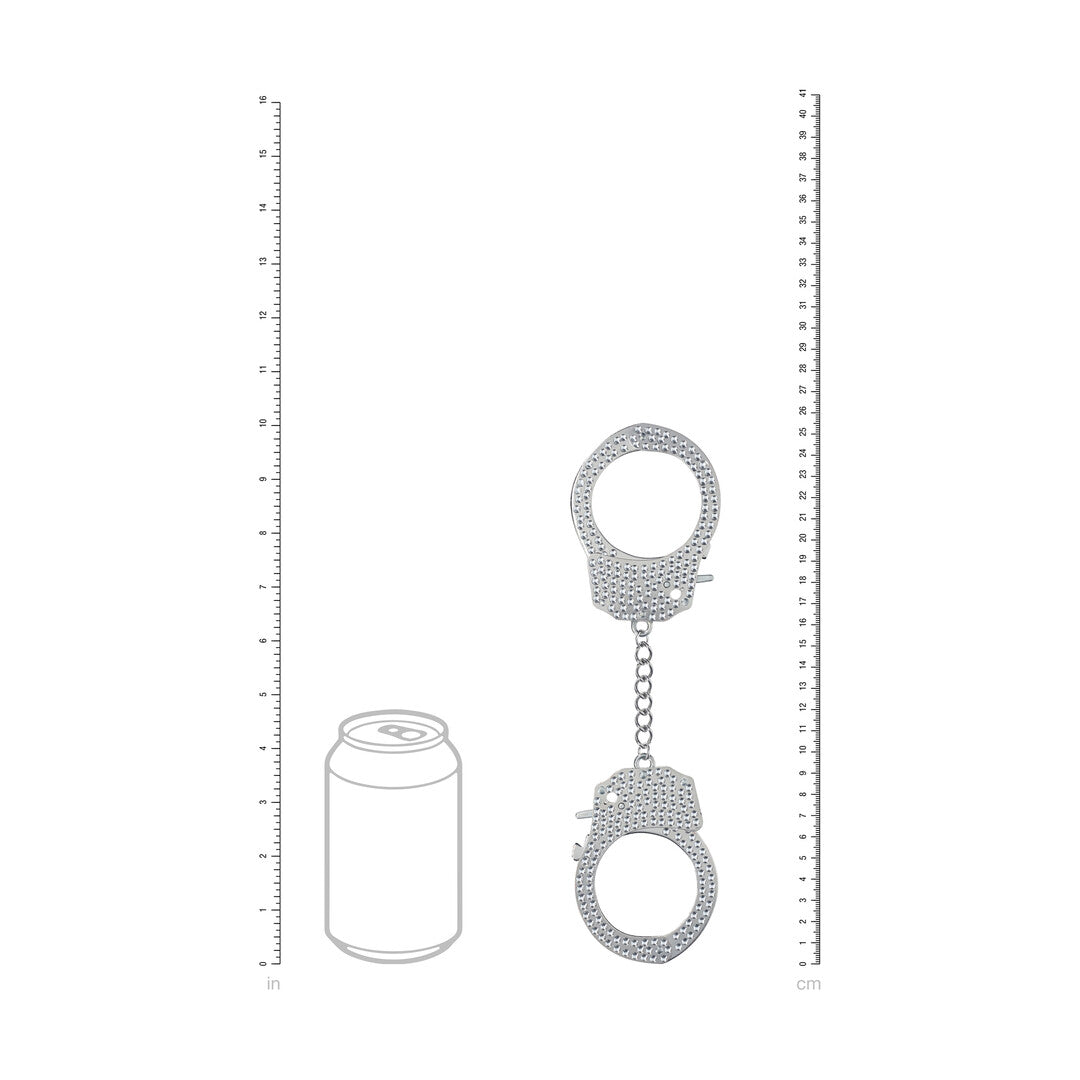 Formaatvergelijking van de Ouch! Diamond Handboeien in zilver naast een blikje en een liniaal