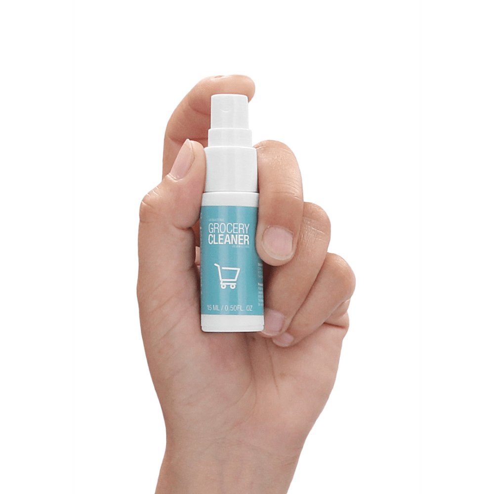 Hand die de Pharmquests Grocery Cleaner 15 ml vasthoudt, kleine desinfectiespray die gericht reinigen