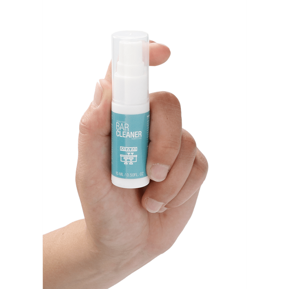 Hand die de Pharmquests Antibacterial Bar Cleaner 15 ml gebruikt, toont compacte sprayfles voor eenvoudige desinfectie