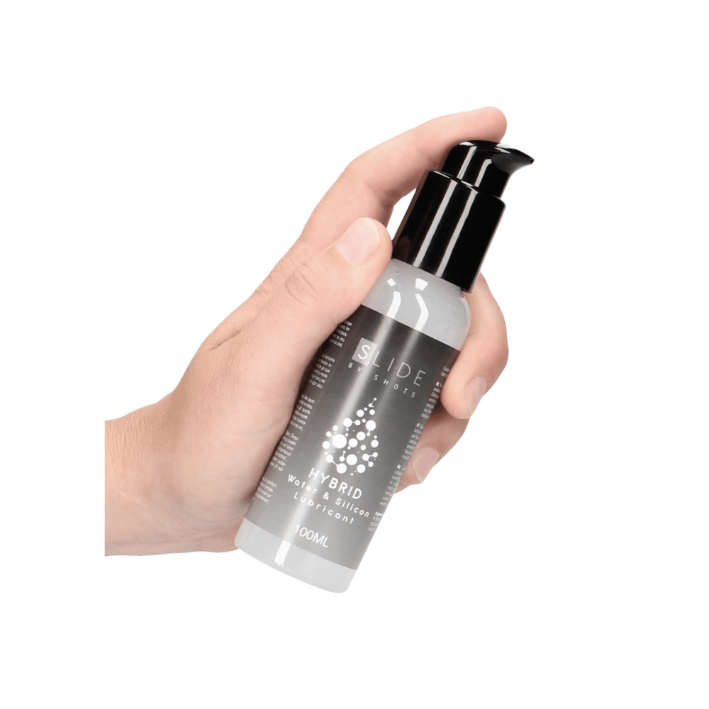 Pharmquests Slide Hybrid glijmiddel 100 ml vastgehouden in de hand, toont handige pomp en zachte hybride formule