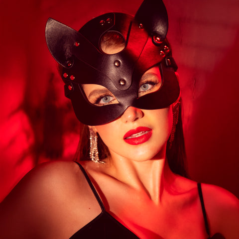 Mapalé zwart oogmasker gedragen in portretbeeld, met open oogvorm en intense rode achtergrond