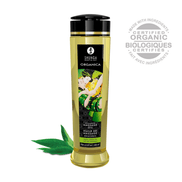 Shunga Organica massageolie groene thee 240 ml, fles met bladdecor en verse groene theebladeren ernaast