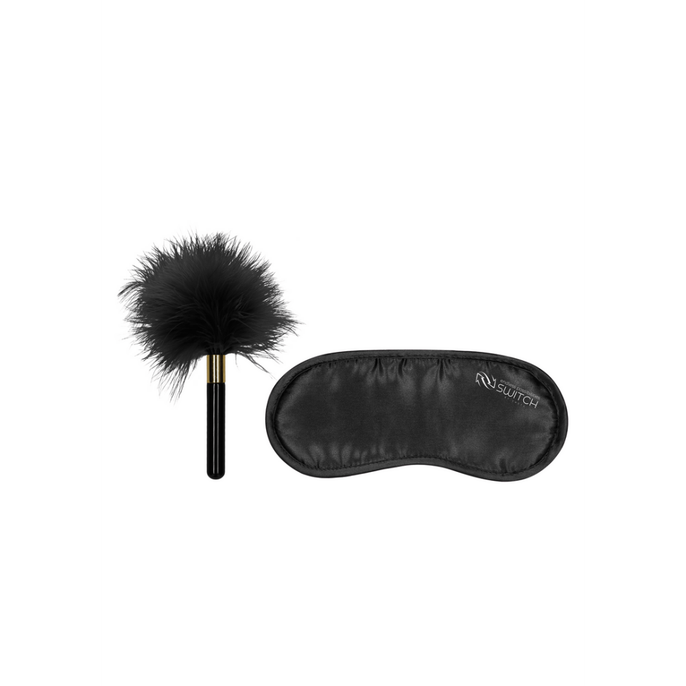Zwarte veren kietelaar met zwart handvat naast zwarte satijnen blinddoek met Switch logo.