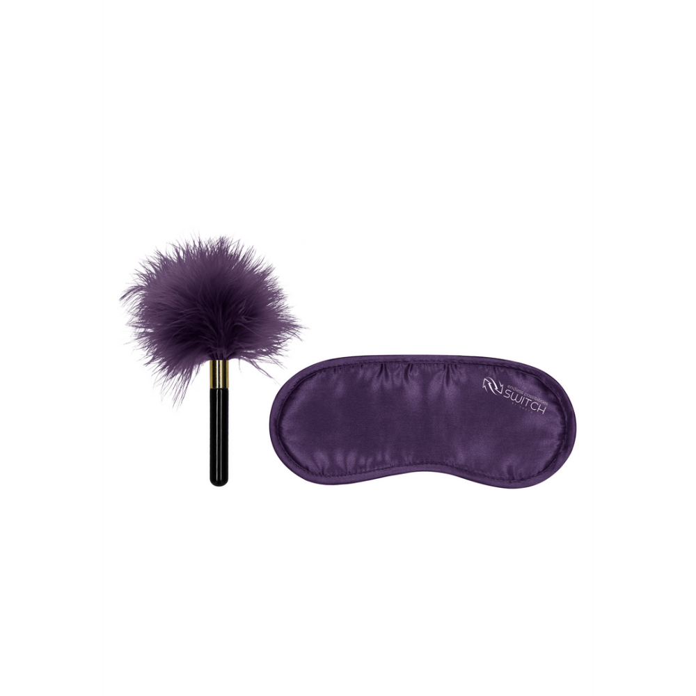 Paarse veren kietelaar met zwart handvat naast paarse satijnen blinddoek met Switch logo.