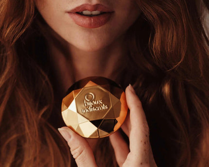 Bijoux Indiscrets Twenty One gouden vibrator in diamantvorm vastgehouden bij gezicht
