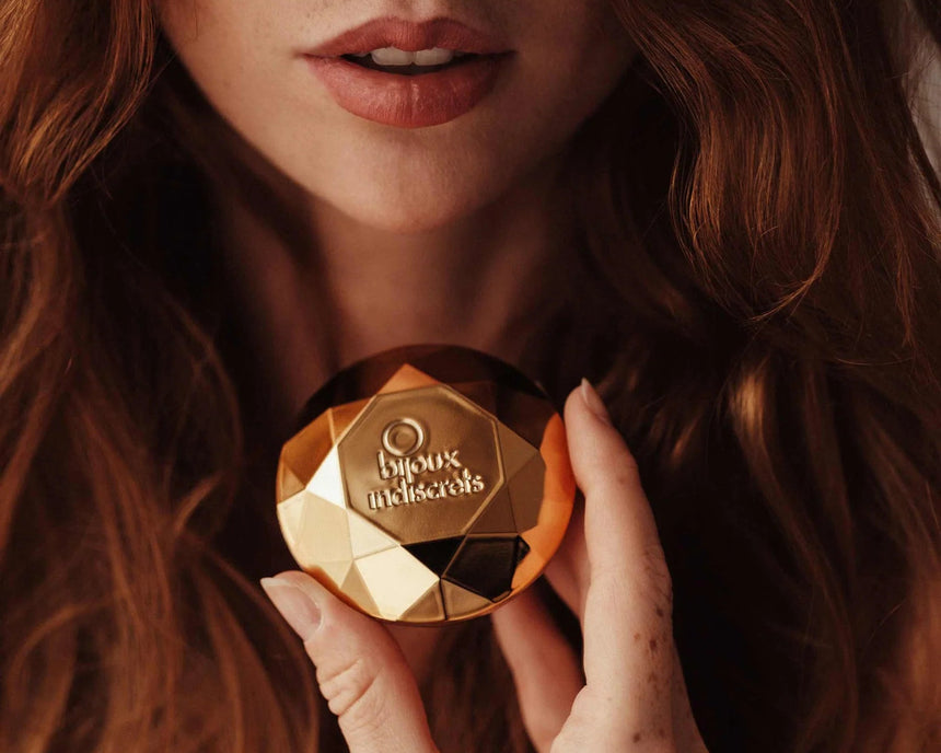Bijoux Indiscrets Twenty One gouden vibrator in diamantvorm vastgehouden bij gezicht