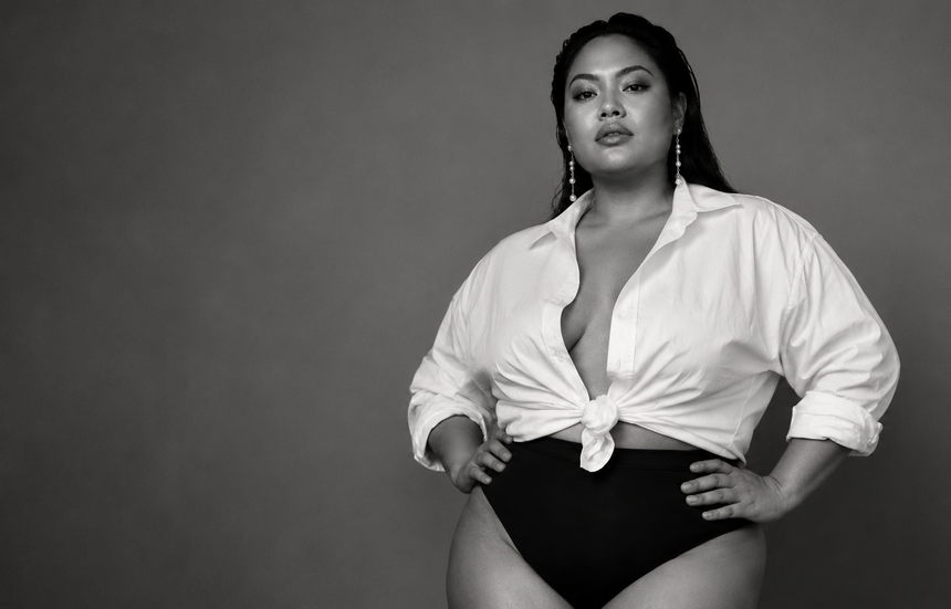 Zelfverzekerde curvy vrouw in zwart-wit, gekleed in een witte blouse en zwarte high-waist lingerie.