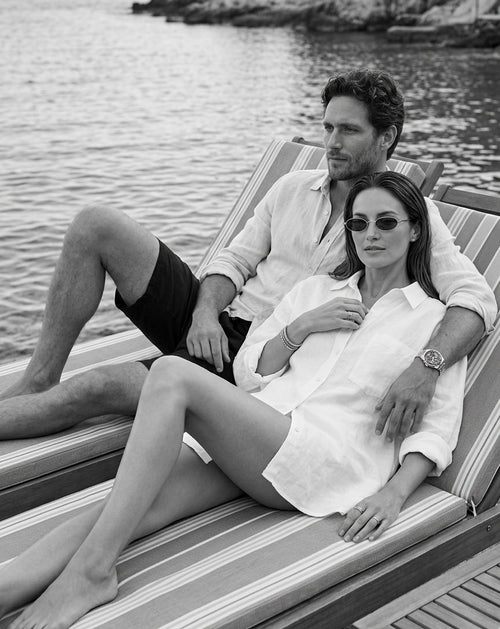 Zwart-wit sfeerbeeld van stijlvol koppel op ligbed aan het water, ontspannen luxe lifestyle
