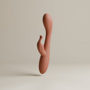Odes Lustra Tarzan vibrator in terracotta, staand in studio met gebogen vorm en kleine stimulator
