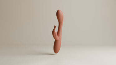 Odes Lustra Tarzan vibrator in terracotta, staand in studio met gebogen vorm en kleine stimulator