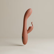 Odes Lustra Tarzan vibrator in terracotta vanuit zijaanzicht, met slanke boog en donker accent aan de basis