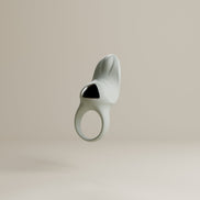 Odes Surrender vibrerende cockring in lichtgrijs, frontaal zwevend met open ring en zwarte accentplaat