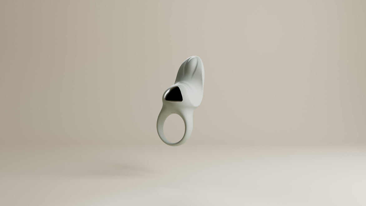 Odes Surrender vibrerende cockring in lichtgrijs, frontaal zwevend met open ring en zwarte accentplaat