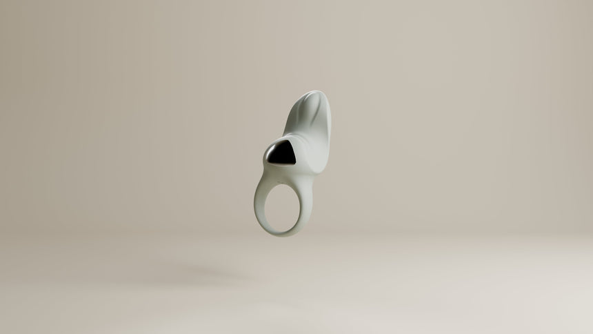 Odes Surrender vibrerende cockring in lichtgrijs, frontaal zwevend met open ring en zwarte accentplaat