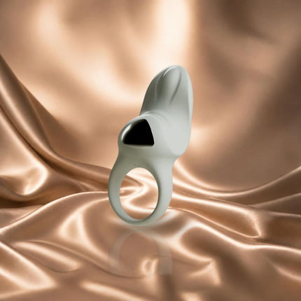 Lichtgrijze Odes Surrender vibrerende ring met zwart detail op champagnekleurig satijn