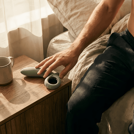 Grijze Odes Swell anale vibrator op een houten nachtkastje, in warme slaapkamer met hand in beeld