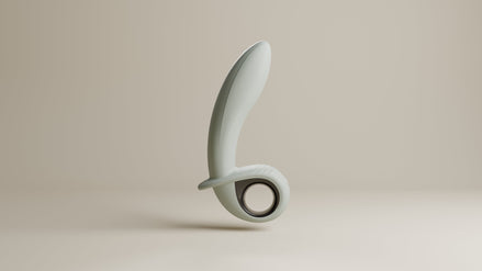 Odes Swell grijze anale vibrator met gebogen vorm, brede basis en ronde ring op beige studioachtergrond