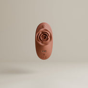 Odes The Touch clitorisvibrator frontaal gefotografeerd, met roosvormige kop, ronde knop en zachte terracotta afwerking