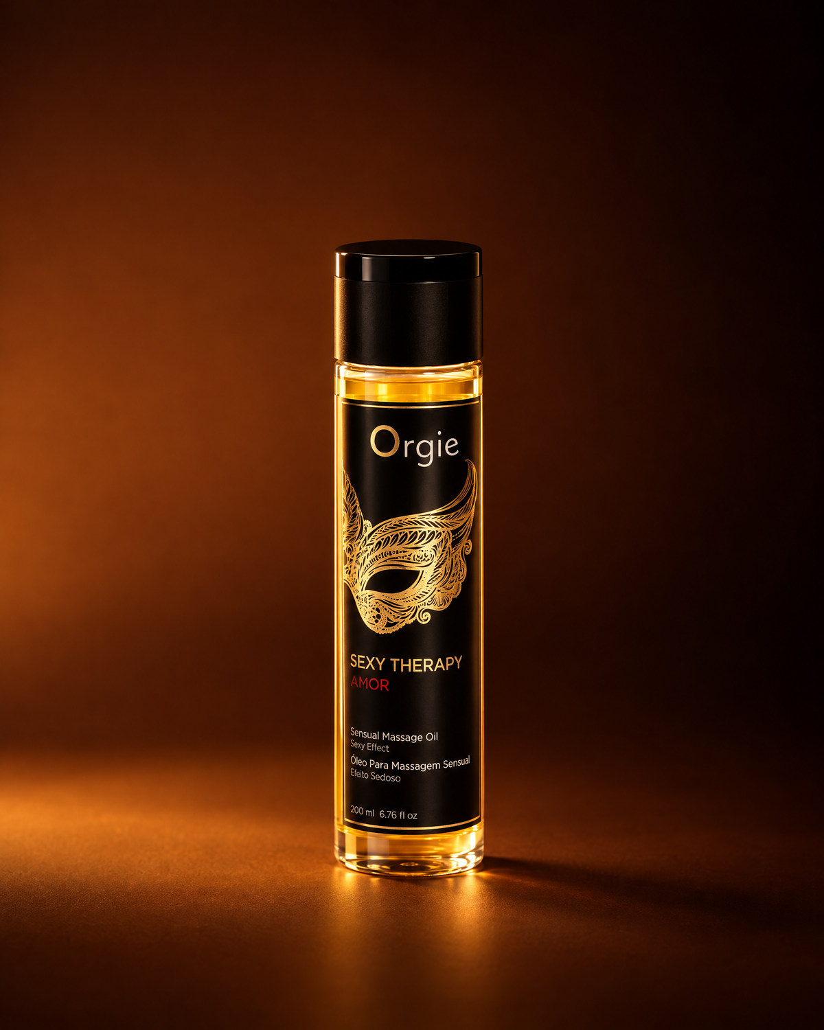 Alt-tekst
Orgie Sexy Therapy Amor massageolie in een transparante fles met goudkleurige olie, zwart etiket met gouden maskerillustratie en zwarte dop, warm uitgelicht tegen een koperbruine achtergrond