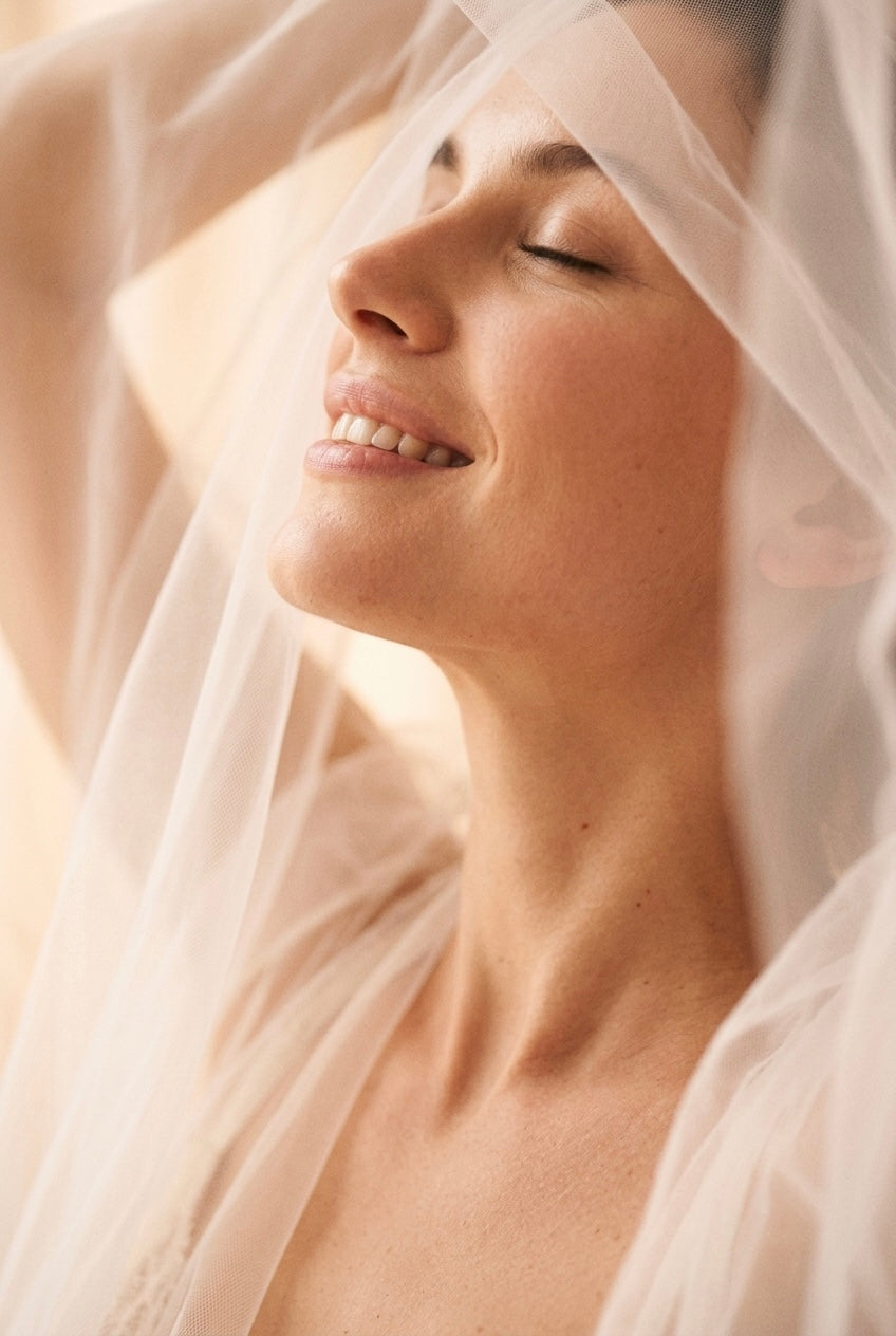 Vrouw met gesloten ogen en een glimlach, gehuld in zachte tule stof, close-up crop, sfeerbeeld bij de Touch-Me lingerie collectie in maat L-XL