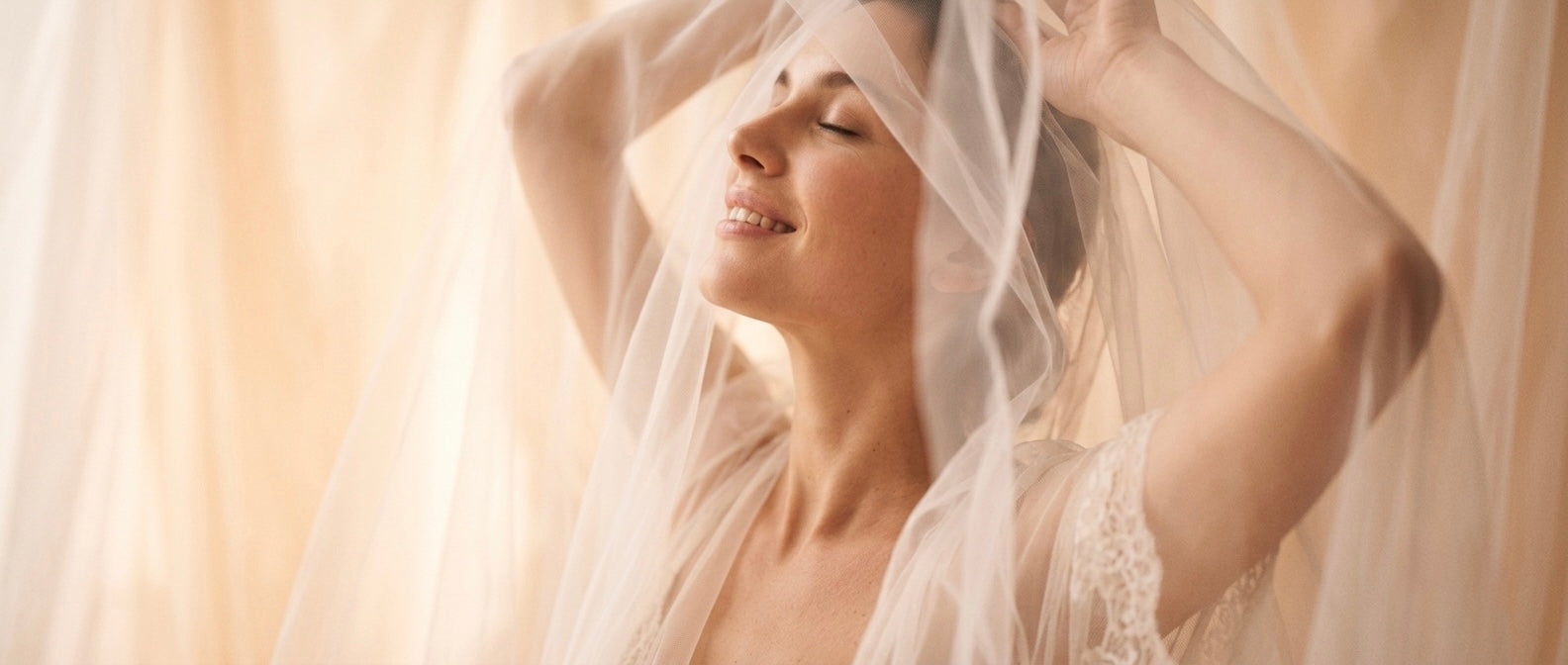 Vrouw met gesloten ogen en een glimlach, gehuld in zachte tule stof en kant, sfeerbeeld bij de Touch-Me lingerie collectie in maat L-XL"