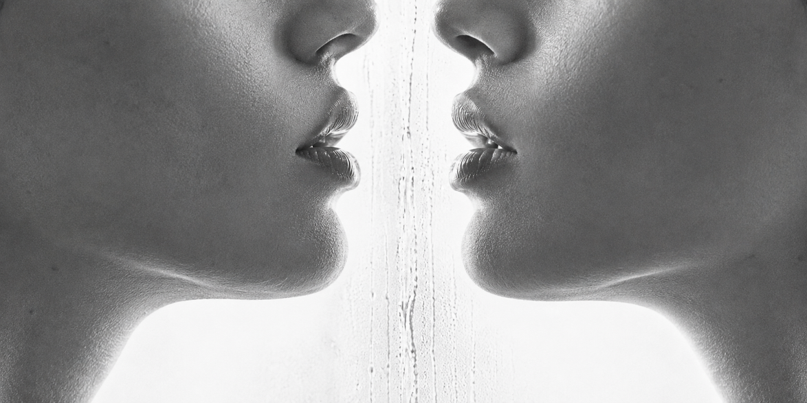 Zwart-wit close-up van twee gezichten die elkaar spiegelen met lippen die elkaar bijna raken, sfeerbeeld bij de Touch-Me lingerie collectie in maat S-M