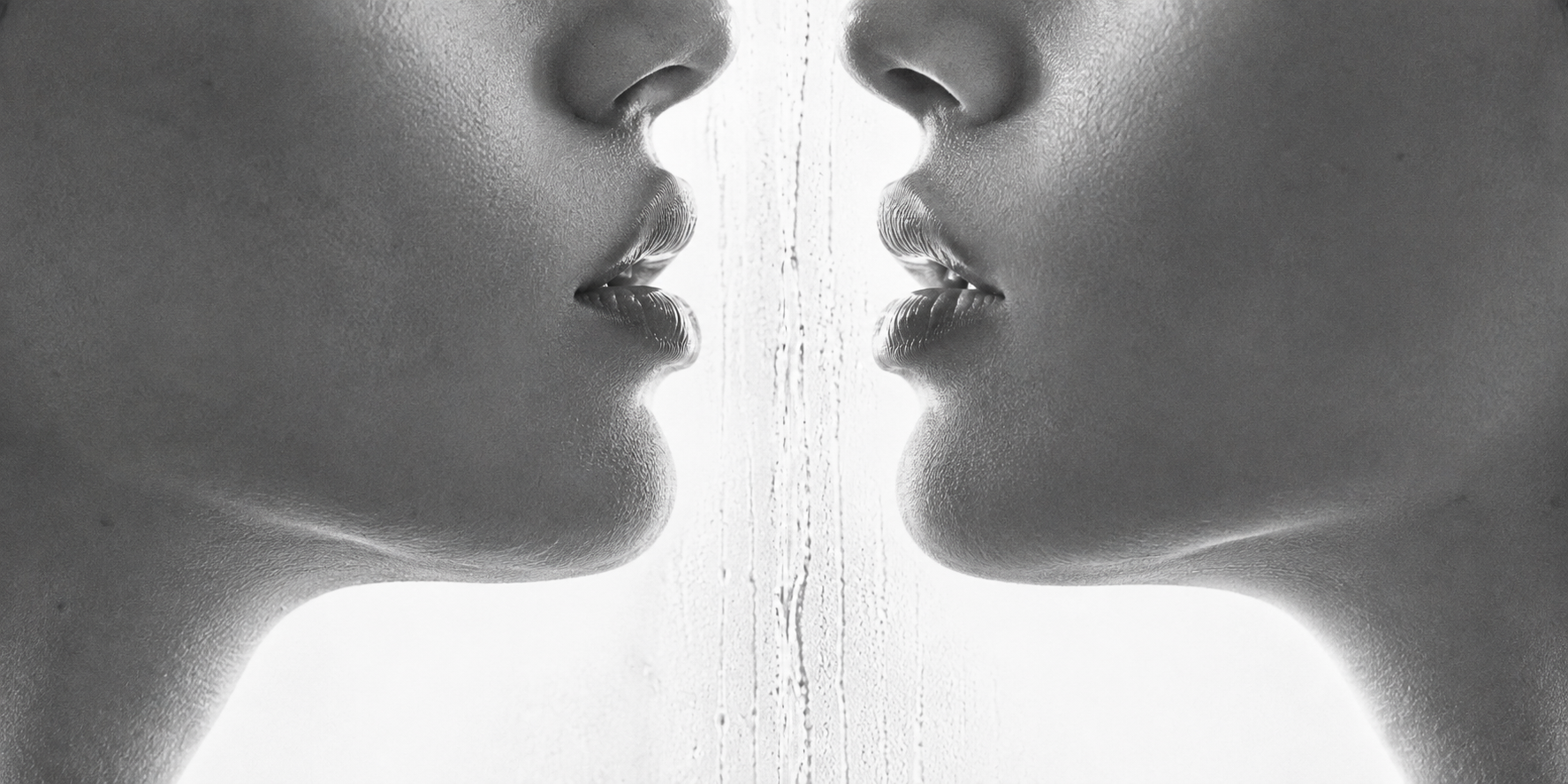 Zwart-wit close-up van twee gezichten die elkaar spiegelen met lippen die elkaar bijna raken, sfeerbeeld bij de Touch-Me lingerie collectie in maat S-M