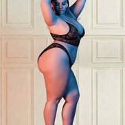 Model in zwarte kanten bh en slip, schuin van opzij in rood en blauw licht